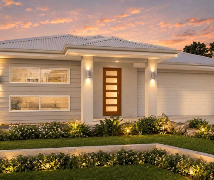 183-Plumbago-Dakota - Fresh Homes Modern single-story home with a wooden front door, warm entrance lighting, and a manicured front garden at sunset.